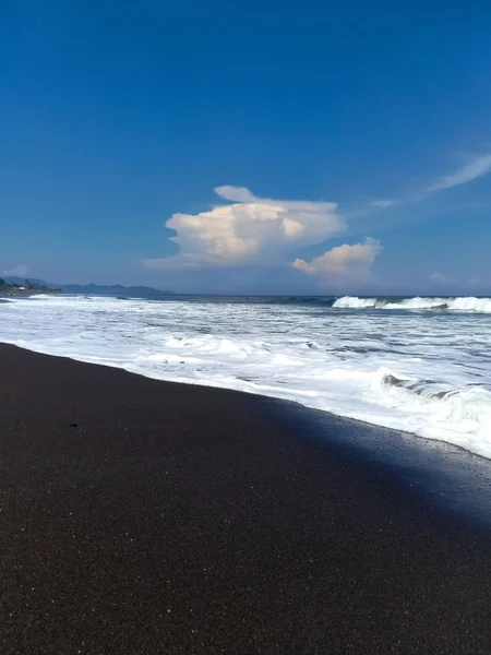 güzel manzara, deniz köpüğü ve beyaz bulutlar mavi gökyüzünde, güneşli gün Amed plaj, Bali Adası üzerinde form dalgalar tarafından yıkanmış siyah volkanik kum Hint Okyanusu kıyısında.