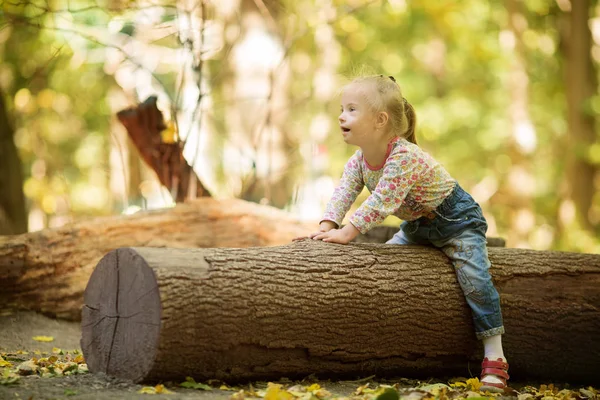 Lustiges Kleines Mädchen Mit Syndrom Sitzt Auf Einem Großen Baumstamm — Stockfoto