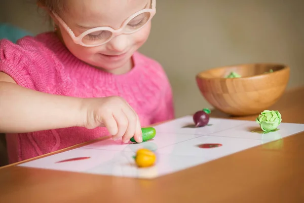 Girl with Down syndrome with interest sorting vegetables