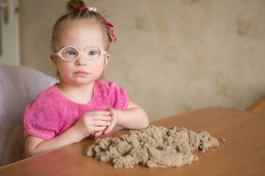 Girl with Down syndrome playing kinetic sand clipart