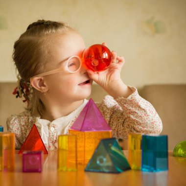 Girl with Down syndrome playing with geometrical shapes clipart