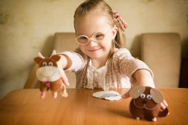 Girl with Down syndrome playing Felt animals developing fine motor skills of fingers clipart