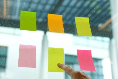 İşyerinde cam duvar üzerine yapışkan notlar işaret ver. Yaratıcı fikir ve iş beyin fırtınası için yapışkan not kağıt hatırlatma programı