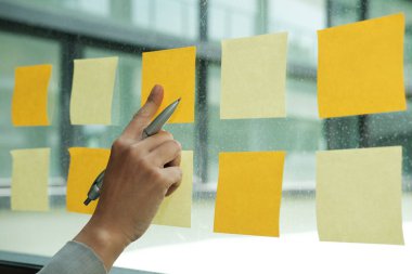 İşyerinde cam duvar üzerine yapışkan notlar işaret ver. Yaratıcı fikir ve iş beyin fırtınası için yapışkan not kağıt hatırlatma programı