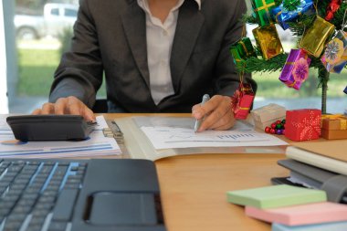 hesap makinesi, işletme belgesi ofisteki çalımakta mali müşavir. muhasebeci muhasebe ve gelir ve bütçe hesaplama yapıyor. hesaplama sırasında Noel yeni yıl tatili yapma muhasebeci