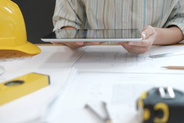 mimar tablet kullanma. gayrimenkul projesi ev planı üzerinde işyerinde çalışan mühendis. İnşaat ve yapı kavramı