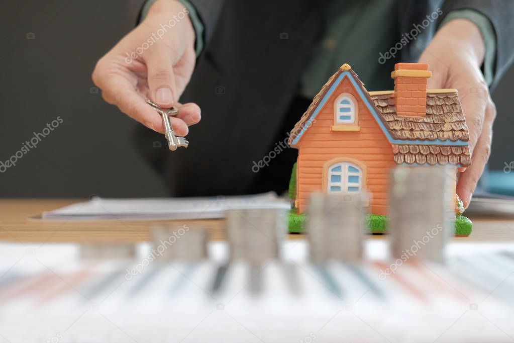 realtor agent with coins stack house model and key. saving money for buying real estate property