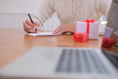 Noel dekorasyon ile adam giyen krem kazak Noel mektubu tatil yazmak istiyor.