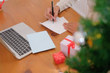 Noel dekorasyon ile adam giyen krem kazak Noel mektubu tatil yazmak istiyor.