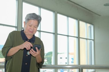 cep telefonu terasta tutan Asya yaşlı kadın. Yaşlı kadın verandada Smartphone kullanarak. cep telefonu ile üst düzey manifatura mesaj
