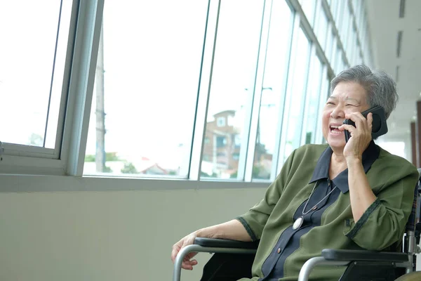 elder woman in wheelchair talk on mobile phone. elderly female speaking on smartphone. asian senior have phone conversation