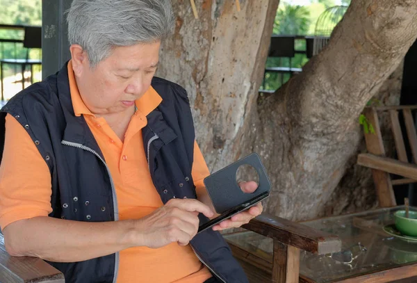 亚洲老年妇女拿着手机在露台上 老年女性老年使用智能手机在天井 — 图库照片