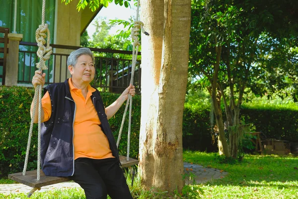 亚洲年长的女性女性放松休息在花园里的秋千上 老年人老年休闲生活方式 — 图库照片