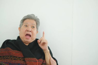 Yaşlı kadın hayran. şok yaşlı kadın. Asya kıdemli beyaz duvara yakın yukarıyı şaşırttı