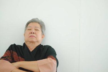 Yaşlı kadın kestiriyor. Asyalı yaşlı kadın kıdemli beyaz duvara yakın uyku uyuklayan