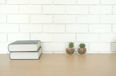 kitap yakınındaki beyaz tuğla duvar ahşap Resepsiyon masasında. Ofis İşyeri üstten görünüm. eğitim kavramı. etli kaktüs bitki tencerede