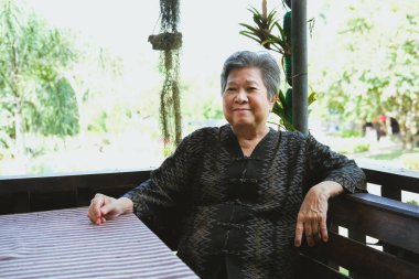 Eski neşeli yaşlı kadın evde rahatlatıcı gülümseyerek. terasta oturup mutlu yaşlı kıdemli