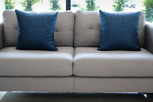 blue fabric pillows on sofa couch furniture in living room near window