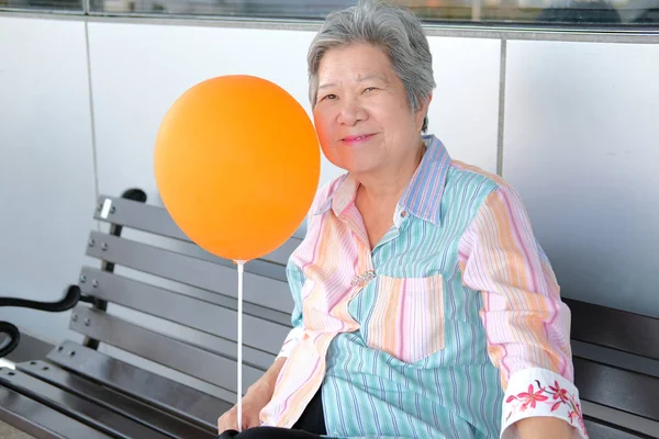 Vecchia donna con un palloncino in mano. asiatico anziani femmina rilassante o — Foto Stock