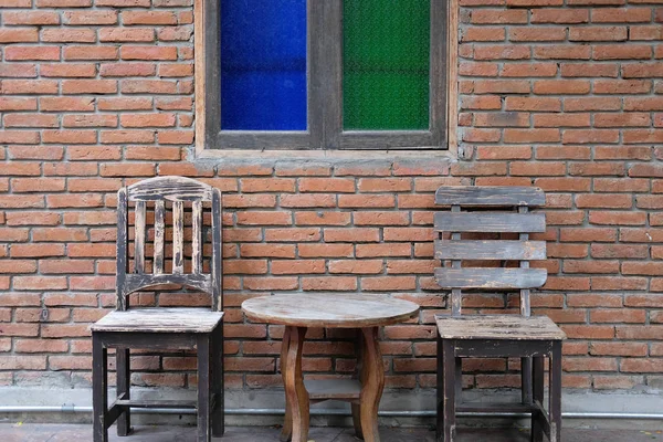 Tuğla duvara yakın eski ahşap masa ve sandalye — Stok fotoğraf