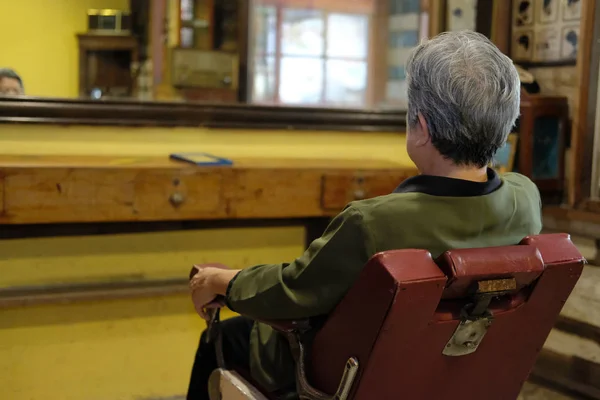 Mulher velha sentar-se na elegante cadeira barbeiro vintage no salão de beleza sh — Fotografia de Stock