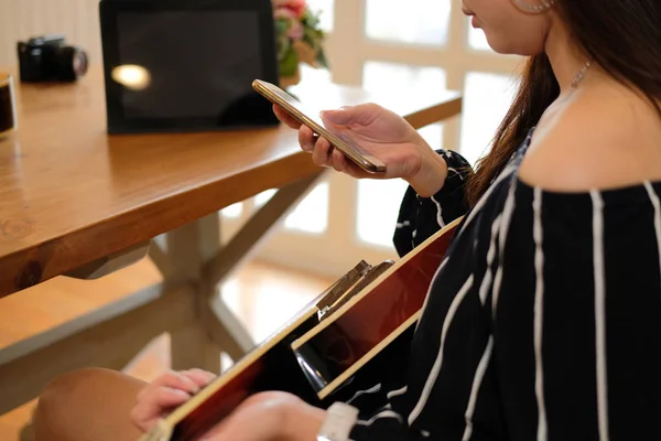 Mobil akıllı telefon kullanarak gitar oynayan kadın — Stok fotoğraf