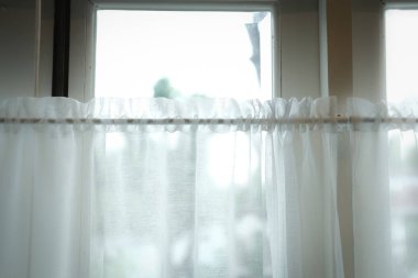 beyaz evde pencere perdesi aracılığıyla görmek