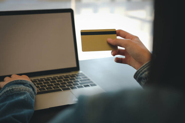 woman holding credit card using computer for shopping online