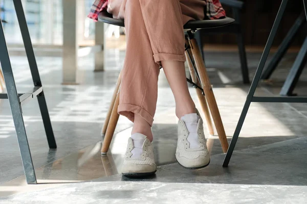 Chica adolescente piernas usando zapatillas de deporte sentado en la cafetería — Foto de Stock