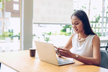 kafe kahve dükkanında mobil akıllı telefon kullanan asyalı kadın