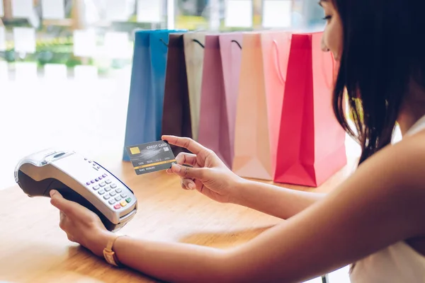 Woman using credit card swiping machine with shopping bags on ta — Stock Photo, Image