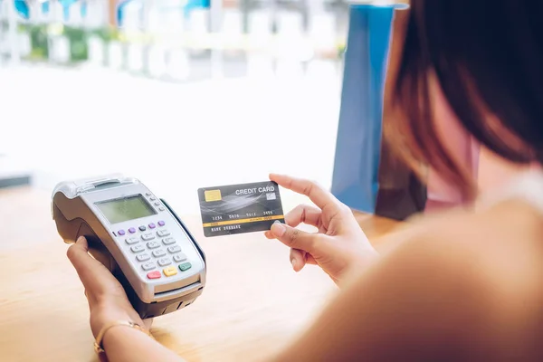 Femme utilisant la machine de balayage de carte de crédit avec des sacs à provisions sur ta — Photo