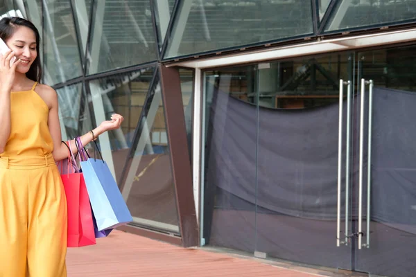 Mujer hablando en smartphone sosteniendo bolsas de la compra. consumismo l — Foto de Stock