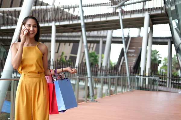 Kvinna talar på smartphone håller shoppingkassar. konsumism — Stockfoto