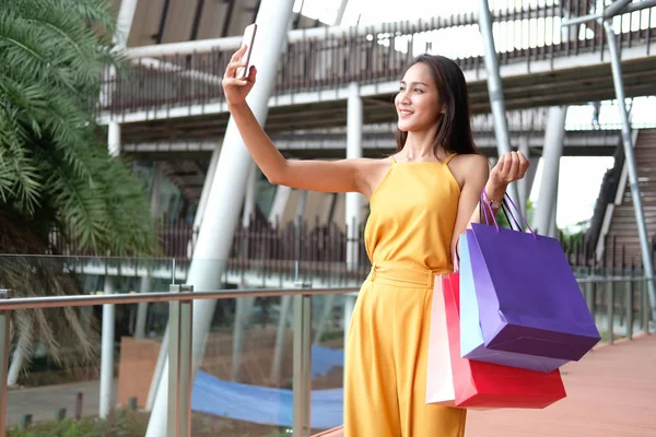 Nő kezében bevásárló táskák csinál szelfi okostelefonnal. Konzu — Stock Fotó