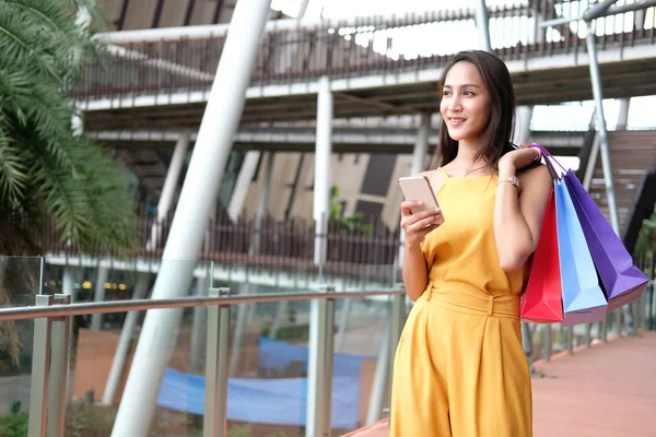 Mujer sosteniendo teléfono inteligente y bolsas de compras. consumismo estilo de vida — Foto de Stock