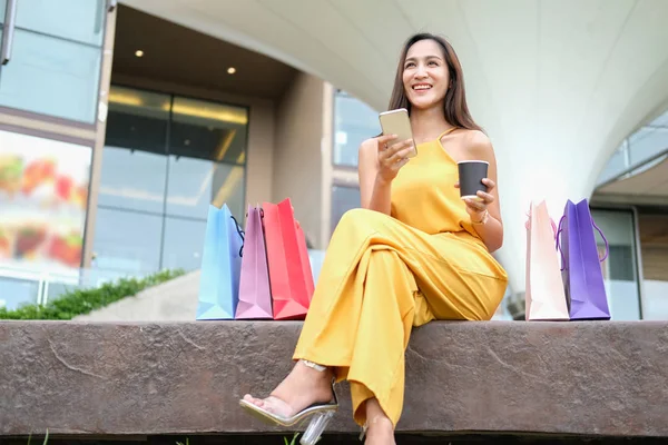 Vrouw met koffiebeker en smartphone met boodschappentassen. consumeren — Stockfoto