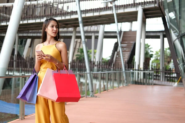 Mujer sosteniendo teléfono inteligente y bolsas de compras. consumismo estilo de vida — Foto de Stock