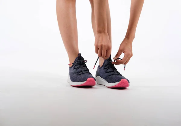 Sport fitness mujer en ropa deportiva atando cordones de zapatos en respaldo blanco — Foto de Stock