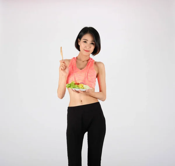 Спортивна фітнес-леді в спортивному одязі з овочевим салатом на білому — стокове фото