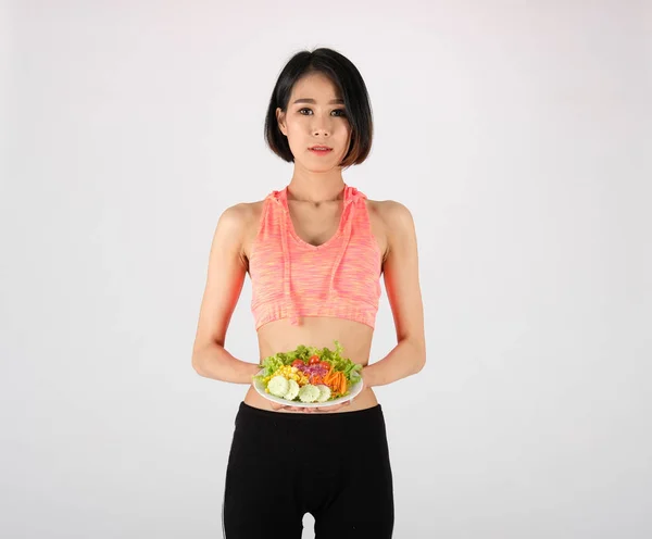 Спортивная спортсменка в спортивной одежде с овощным салатом на белом — стоковое фото