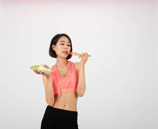 Femme de fitness sportive en vêtements de sport avec salade de légumes sur blanc — Photo