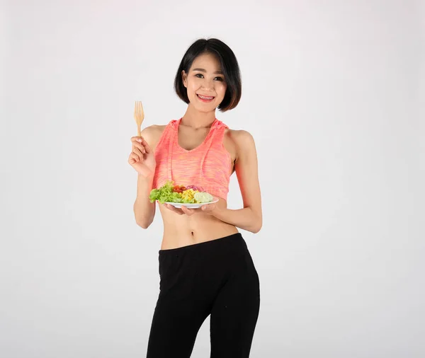 Femme de fitness sportive en vêtements de sport avec salade de légumes sur blanc — Photo