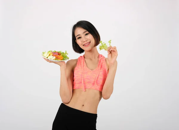 Femme de fitness sportive en vêtements de sport avec salade de légumes sur blanc — Photo