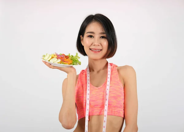 Sportiva donna fitness in abbigliamento sportivo con insalata di verdure su bianco — Foto Stock