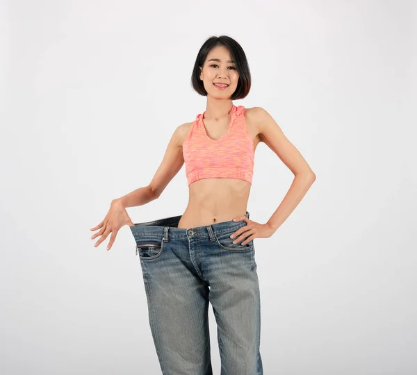 Sportivo fitness donna in jeans sciolti dopo aver perso peso su bianco — Foto Stock