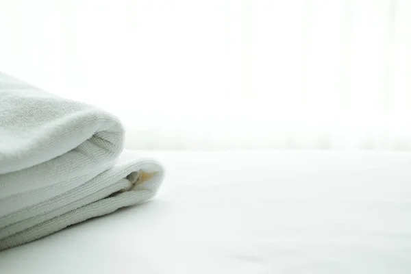 Witte handdoek op bed met doorzien gordijn achtergrond. — Stockfoto