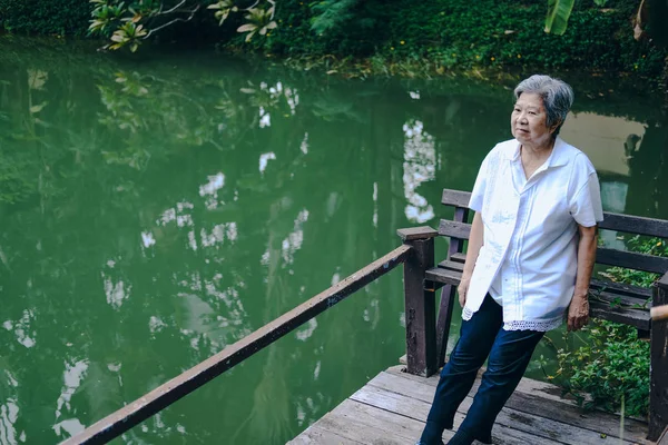 연못 근처에 누워 있는 늙은 부인. 긴장을 풀고 있는 연로 한 여성 — 스톡 사진