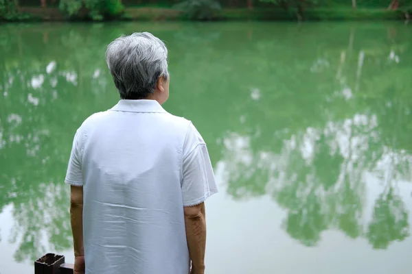 연못 근처에 누워 있는 늙은 부인. 긴장을 풀고 있는 연로 한 여성 — 스톡 사진