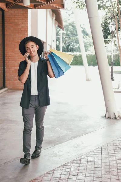 Homem segurando sacos de compras & falando no telefone inteligente móvel . — Fotografia de Stock